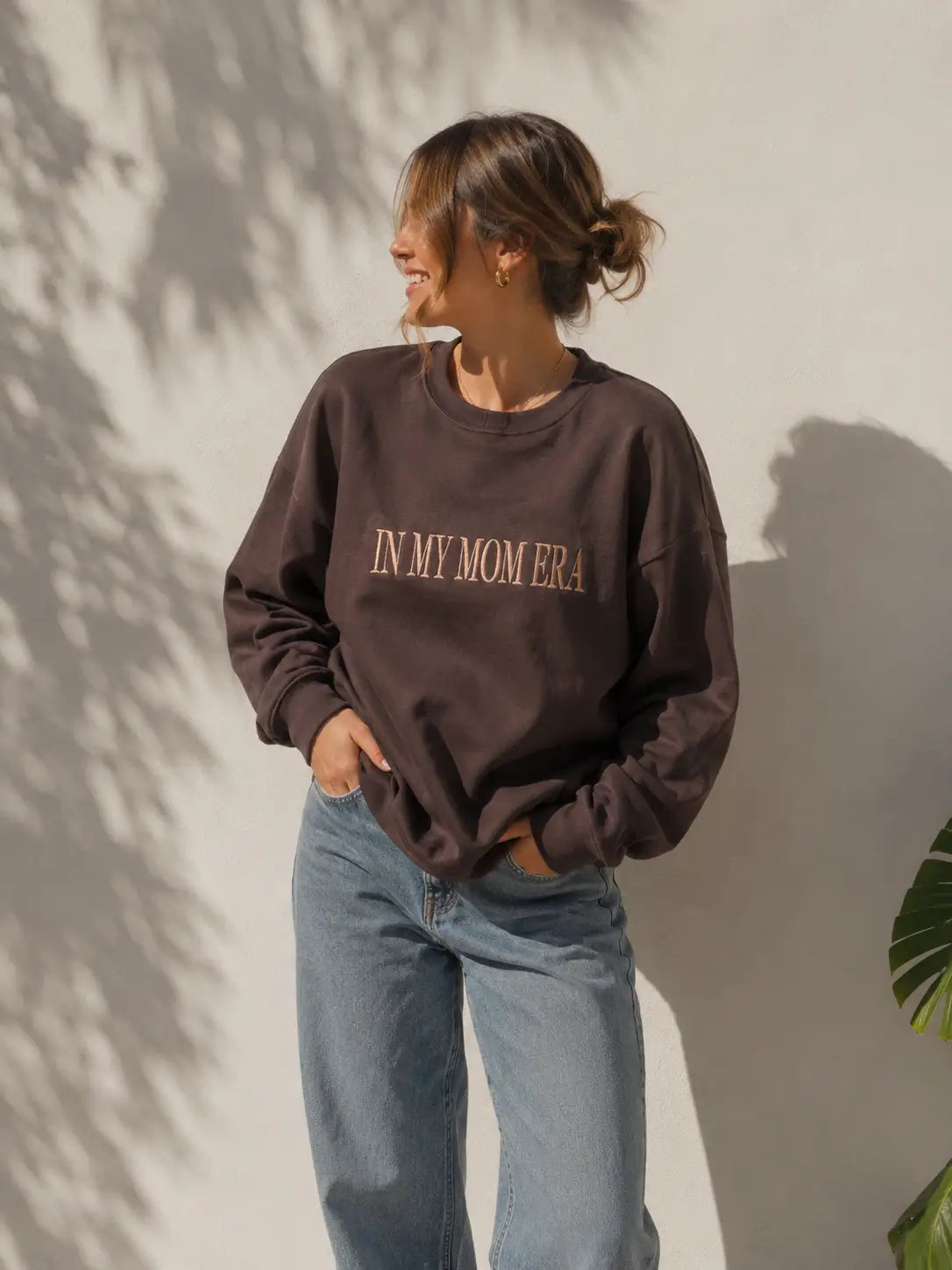 Eine Frau trägt einen personalisierten Sweater mit der Stickerei vorne "IN MY MOM ERA".