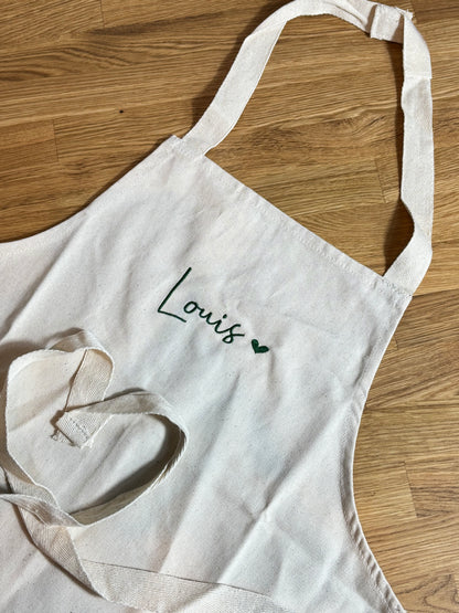Die Junior Schürze ist mit Louis und einem Herz bestickt. 
