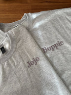 Zwei Sweater in der Farbe Ash Heather mit einer Stickerei jeweils auf der linken Brustseite: Jojo und Boppie.
