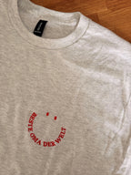 Ein T-Shirt in der Farbe Ash Heather mit kurzen Ärmeln und einen roten Smiley auf der linken Brustseite. Die Grafik besteht aus zwei kleinen ovalen Augen und einem geschwungenen Schriftzug BESTE OMA DER WELT, der ein lächelndes Gesicht bildet.