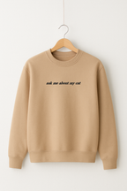 Ein beiger bestickter Pullover mit dem Wunschtext "ask me about my cat".