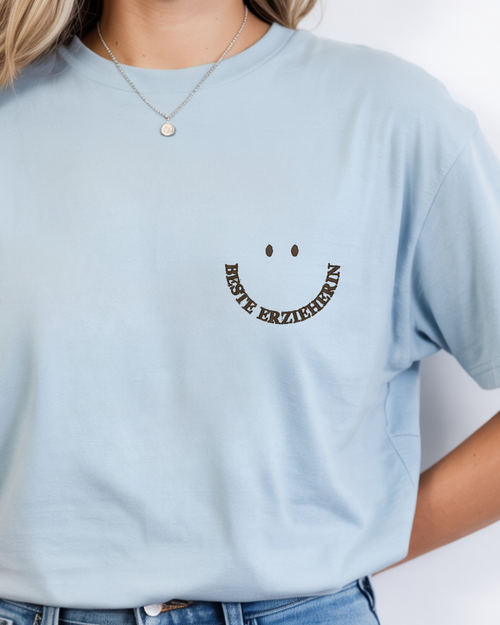 Ein T-Shirt in der Farbe Light Blue mit einem Smiley auf der linken Brust mit der Schrift "Beste Erzieherin".