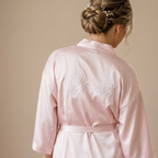 Ein personalisierter Satin-Mantel für die Braut. Die Stickerei hinten "Braut" verleiht dem Ganzen Persönlichkeit.