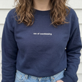 Eine Frau, die einen personalisierten Sweater mit einer Stickerei "ceo of overthinking" trägt.