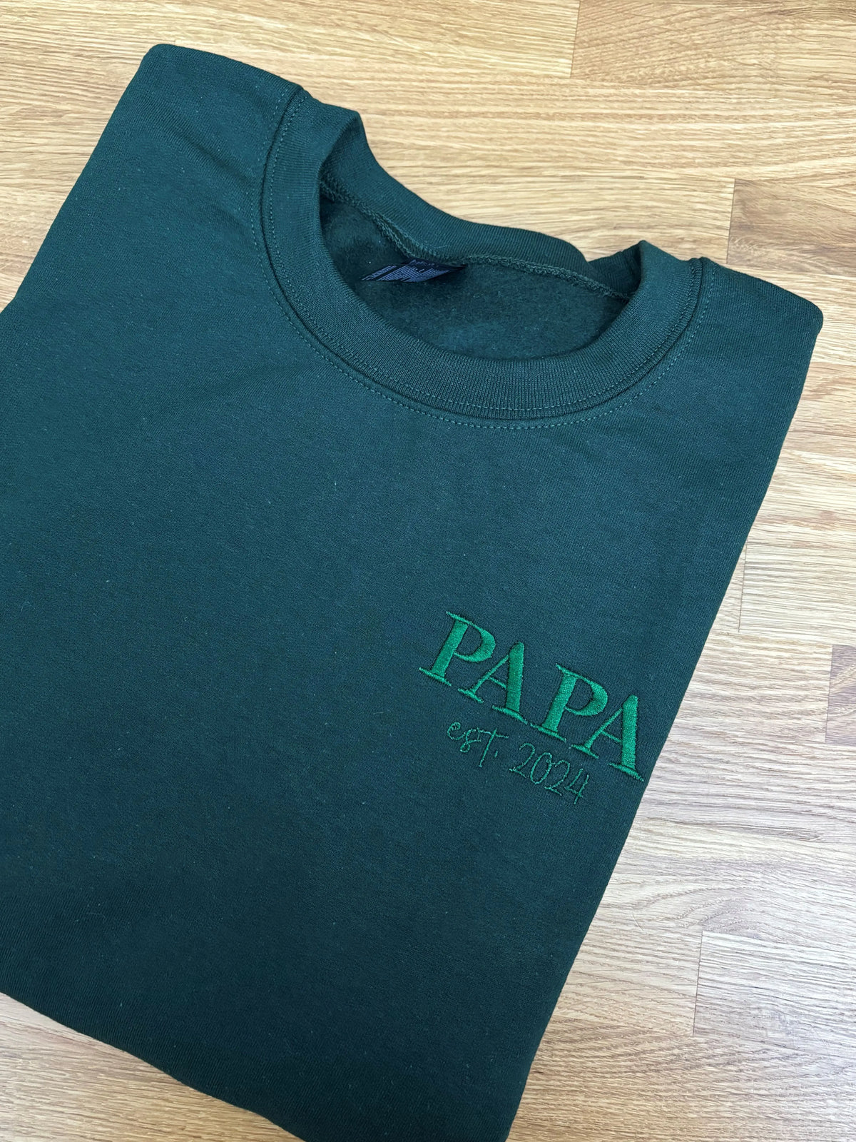 Ein Sweater in der Farbe Forest Green mit einer Stickerei in der Farbe Forest Green: PAPA est. 2024.
