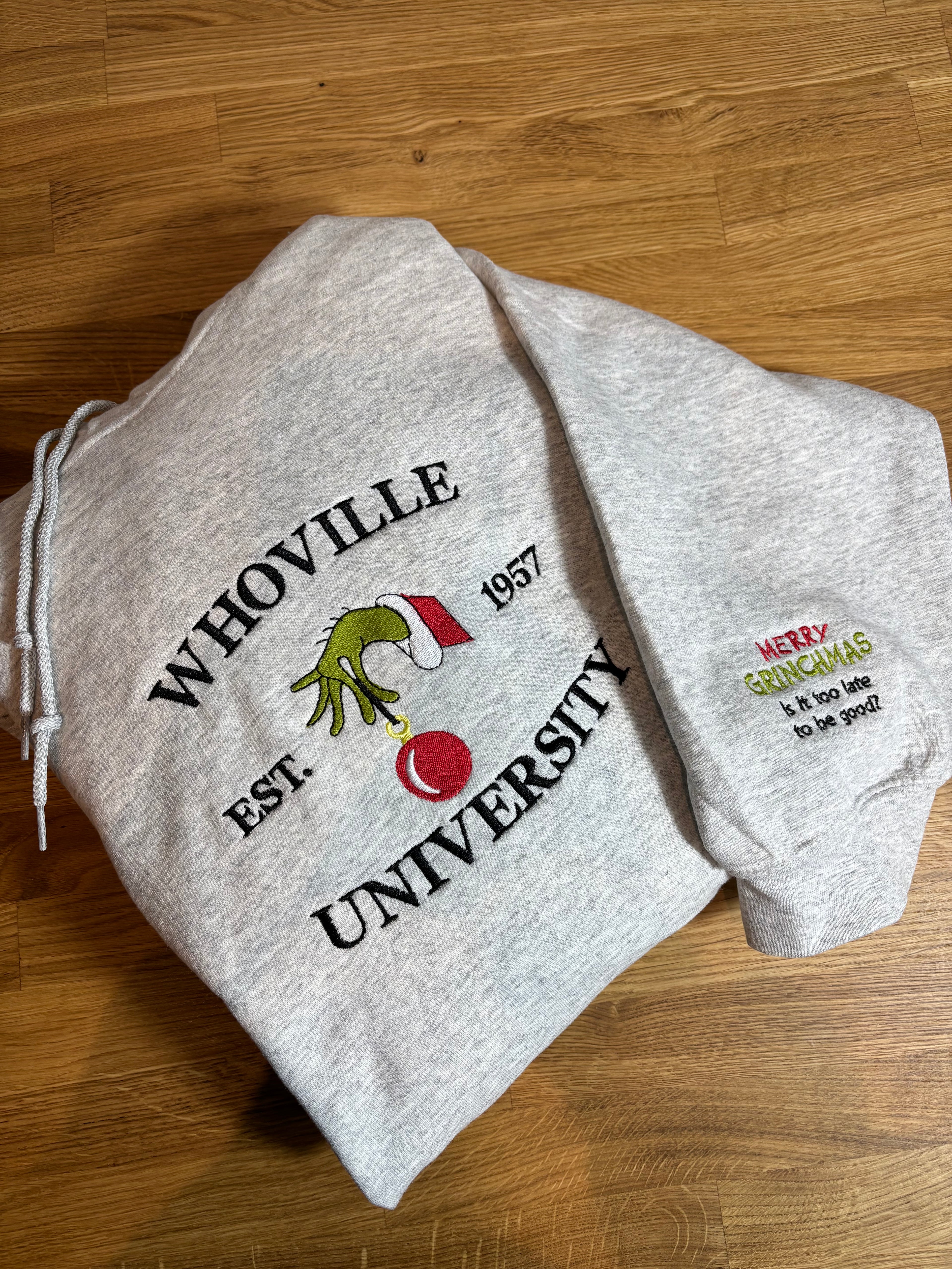 Der Whoville University Grinch Pullover in der Farbe Ash Heather. Der Hoodie ist Unisex und von Innen sehr flauschig. Den Hoodie gibt es als Sweater oder als Pullover mit Kapuze. Auf dem Ärmel ist noch ein Grinch Spruch gestickt: Merry Grinchmas It's too late to be good?