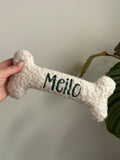 Ein kleiner personalisierte Hundeknochen als kuscheliges Kissen. Der Knochen ist mit dem Namen des verstorbenen Hundes Meilo bestickt.
