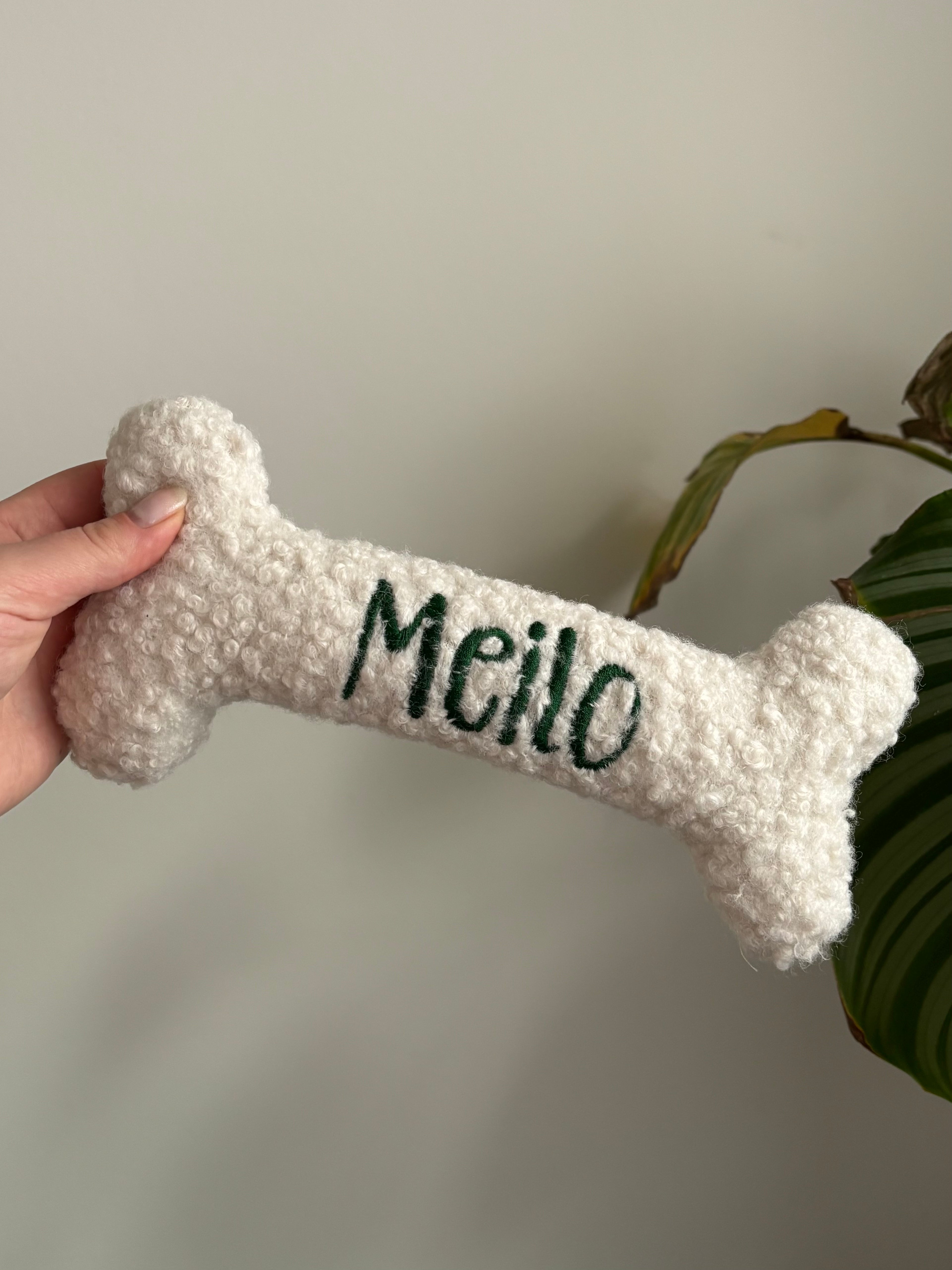 Ein kleiner personalisierte Hundeknochen als kuscheliges Kissen. Der Knochen ist mit dem Namen des verstorbenen Hundes Meilo bestickt.