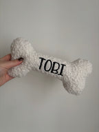 Ein großer personalisierte Hundeknochen als kuscheliges Kissen. Der Knochen ist mit dem Namen des Hundes Tobi bestickt.