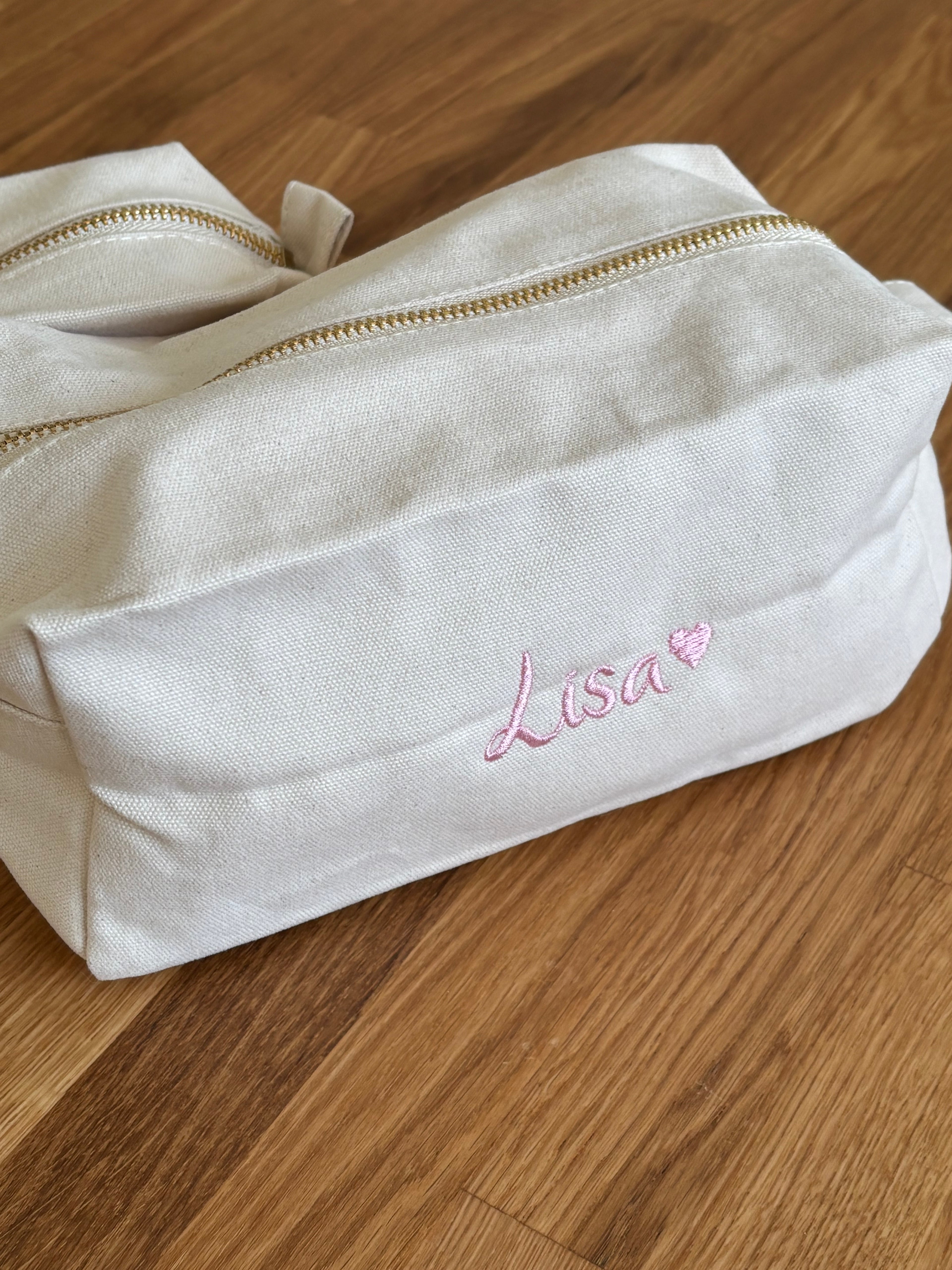 Ein personalisierter Kulturbeutel mit einem rosa Stick Lisa mit einem Herz. 