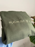 Ein Sweater in der Farbe Military Green mit einer Stickerei in Moss auf der Brust: Mama.