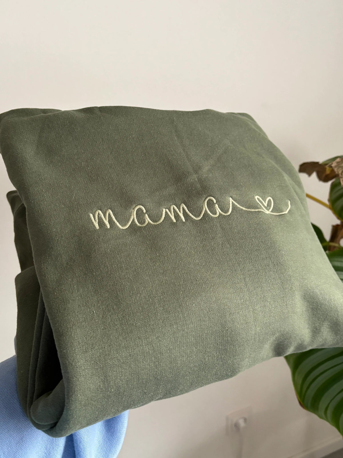 Ein Sweater in der Farbe Military Green mit einer Stickerei in Moss auf der Brust: Mama.
