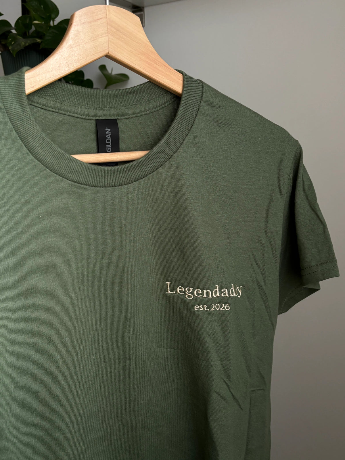 Ein besticktes T-Shirt in der Farbe Military Green „Legendaddy est. 2026“ in beige.