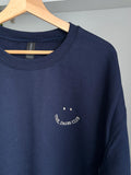 Ein Sweater in der Farbe Navy Blue mit einer beigen Stickerei vorne auf der Brust in der Form eines Smileys: Cool Dads Club.
