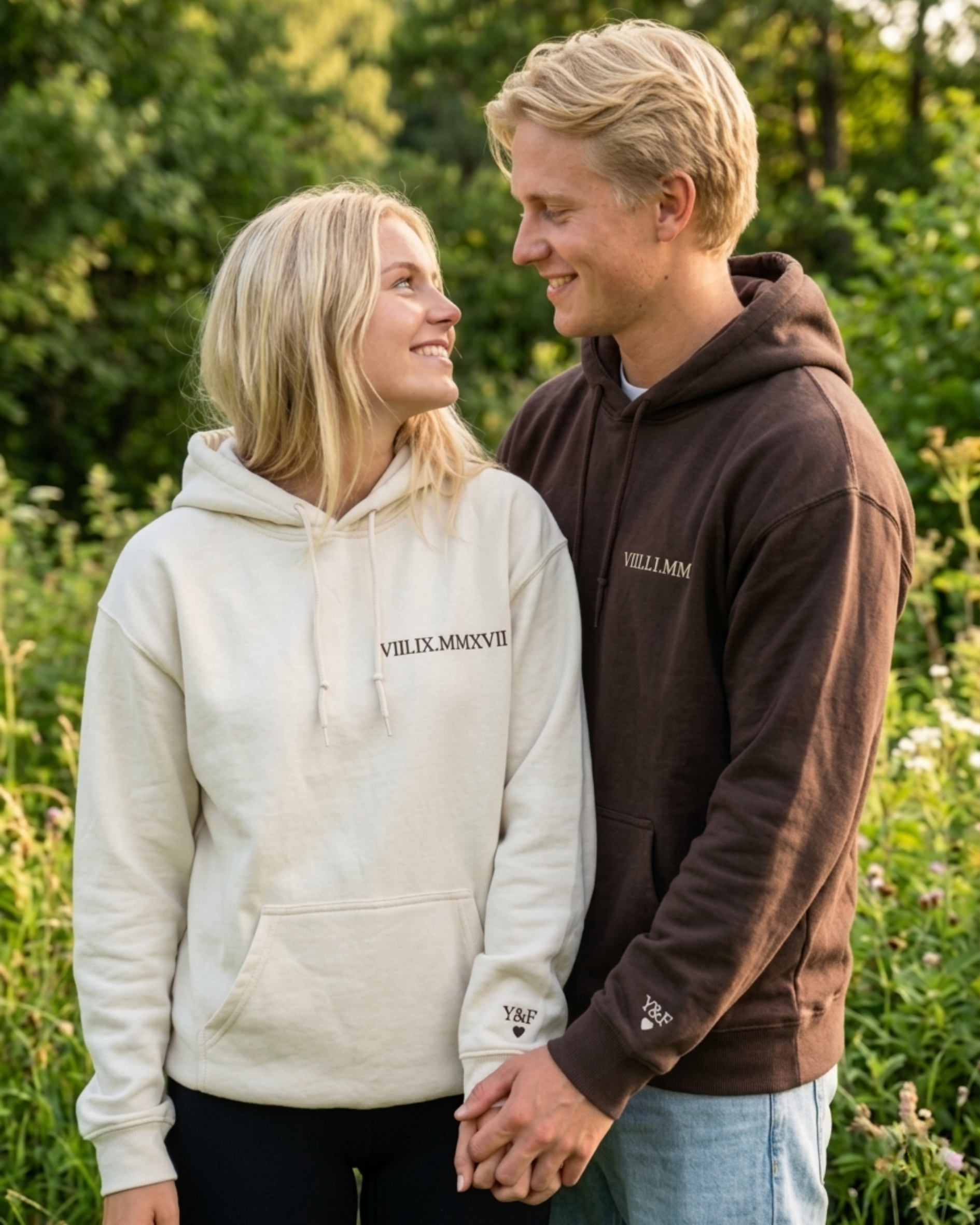 Ein Pärchen welches personalisierte Hoodies tragen. Die Hoodies sind am Ärmel mit Initialen und an der Brust mit dem Jahrestag in römischen Zahlen bestickt.