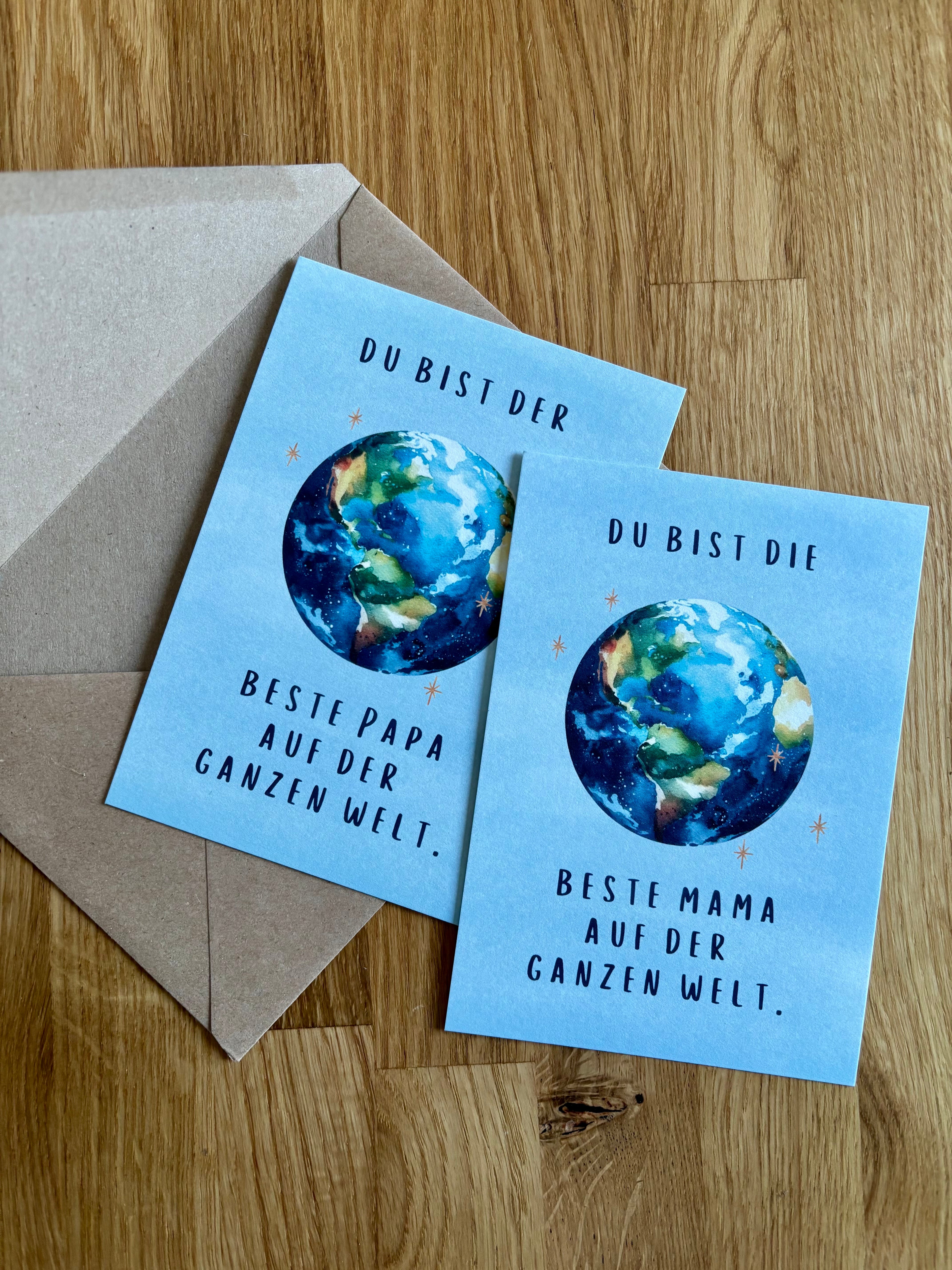 Die zwei Postkarten gibt es in zwei Versionen: Du bist der beste Papa auf der ganzen Welt oder Du bist die beste Mama auf der ganzen Welt. Die Karten haben einen blauen Hintergrund und es ist mittig eine Erde mit Sternen platziert.