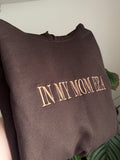 Ein Hoodie in der Farbe Dark Chocolate mit dem Wunschtext „IN MY MOM ERA“ in der Garnfarbe Brown.