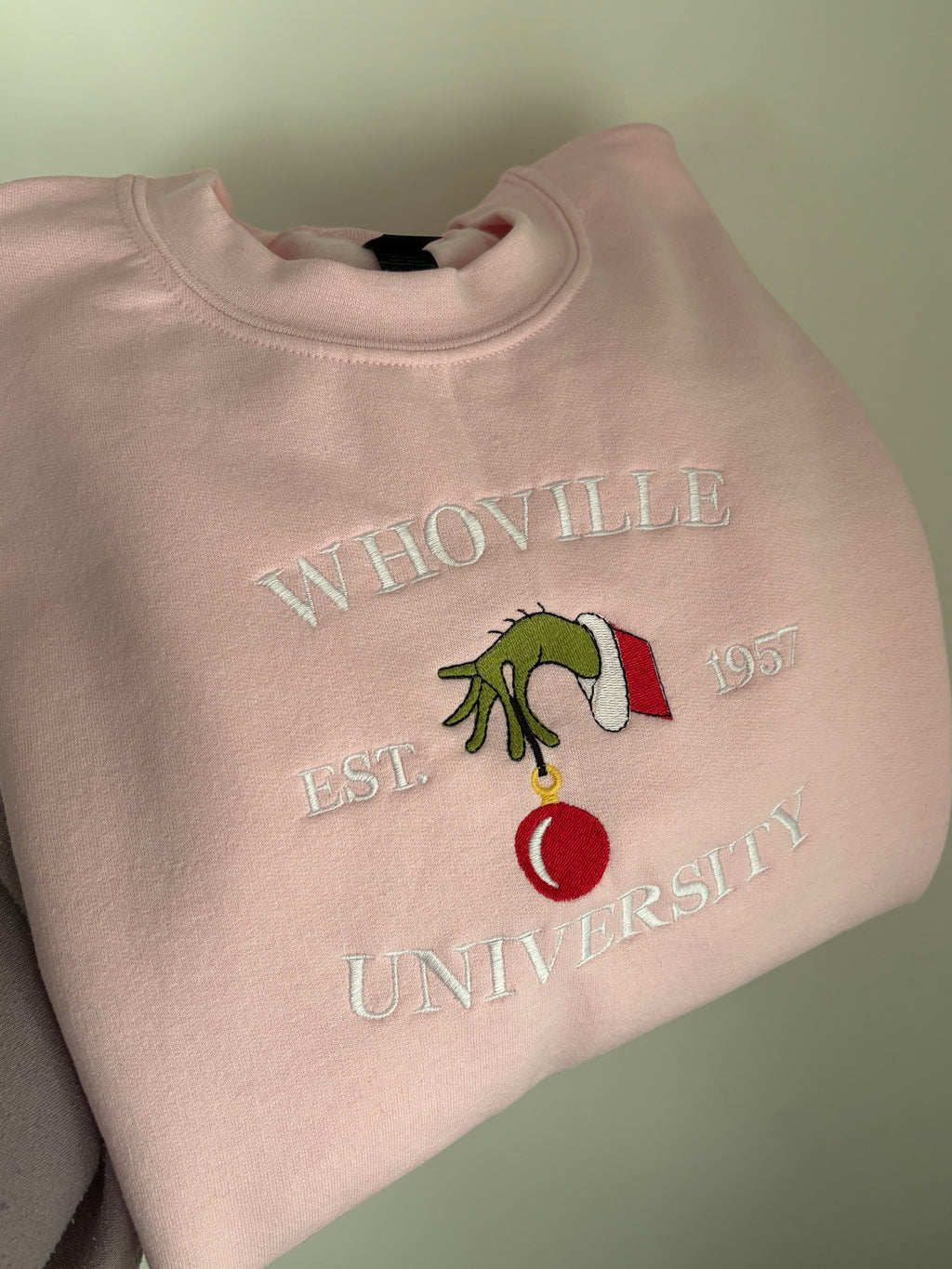 Der Whoville University Grinch Sweater in der Farbe Rosa. Der Pullover ist Unisex und von Innen sehr flauschig. 