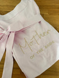 Ein rosa Satin Morgenmantel mit einer beigen Stickerei hinten auf dem Rücken: Mother of the Bride.