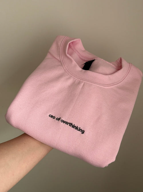 Ein Sweater in der Farbe Rosa mit einer Stickerei vorne mittig "ceo of overhinking" in dunkelgrau.