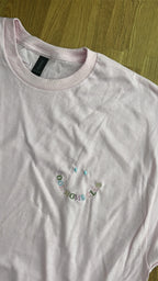 Ein rosanes T-Shirt mit einem Smiley bestickt "COOL MOMS CLUB".