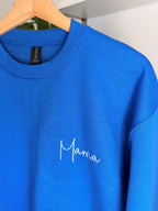 Ein Sweater in der Farbe Royal Blue mit einer weißen Stickerei vorne links auf der Brust: Mama.