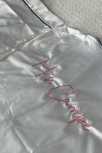 Ein weißer Satin Pyjama mit einer individuellen Bestickung auf dem Rücken in der Garnfarbe Rosa "Mrs. Campe".