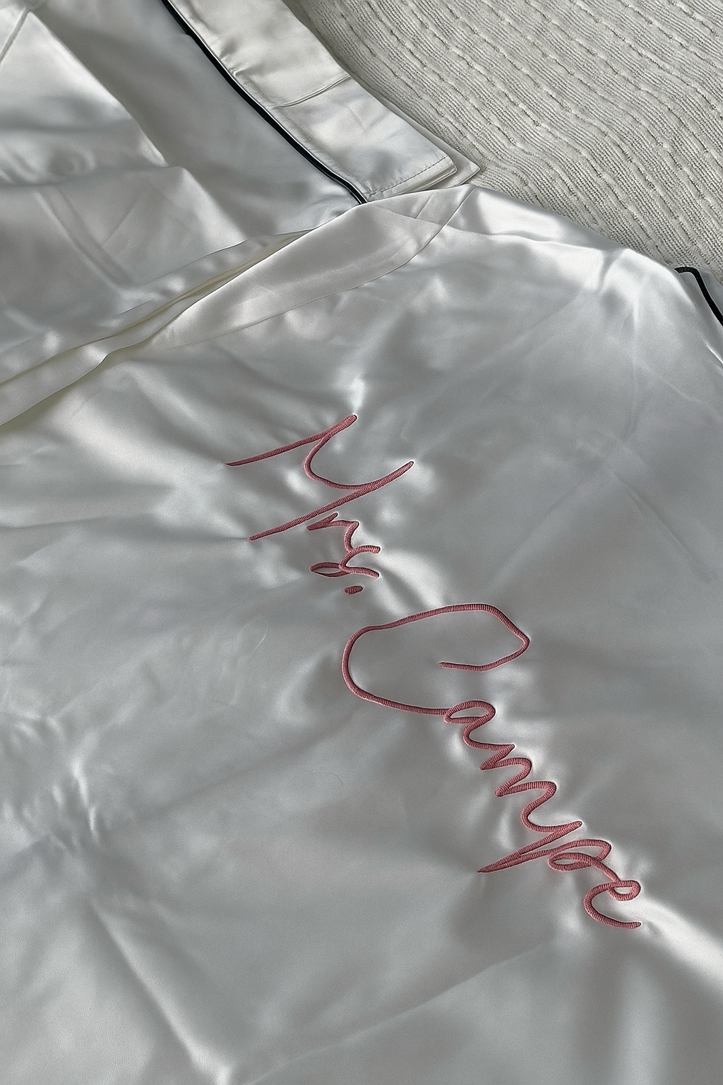 Ein weißer Satin Pyjama mit einer individuellen Bestickung auf dem Rücken in der Garnfarbe Rosa "Mrs. Campe".