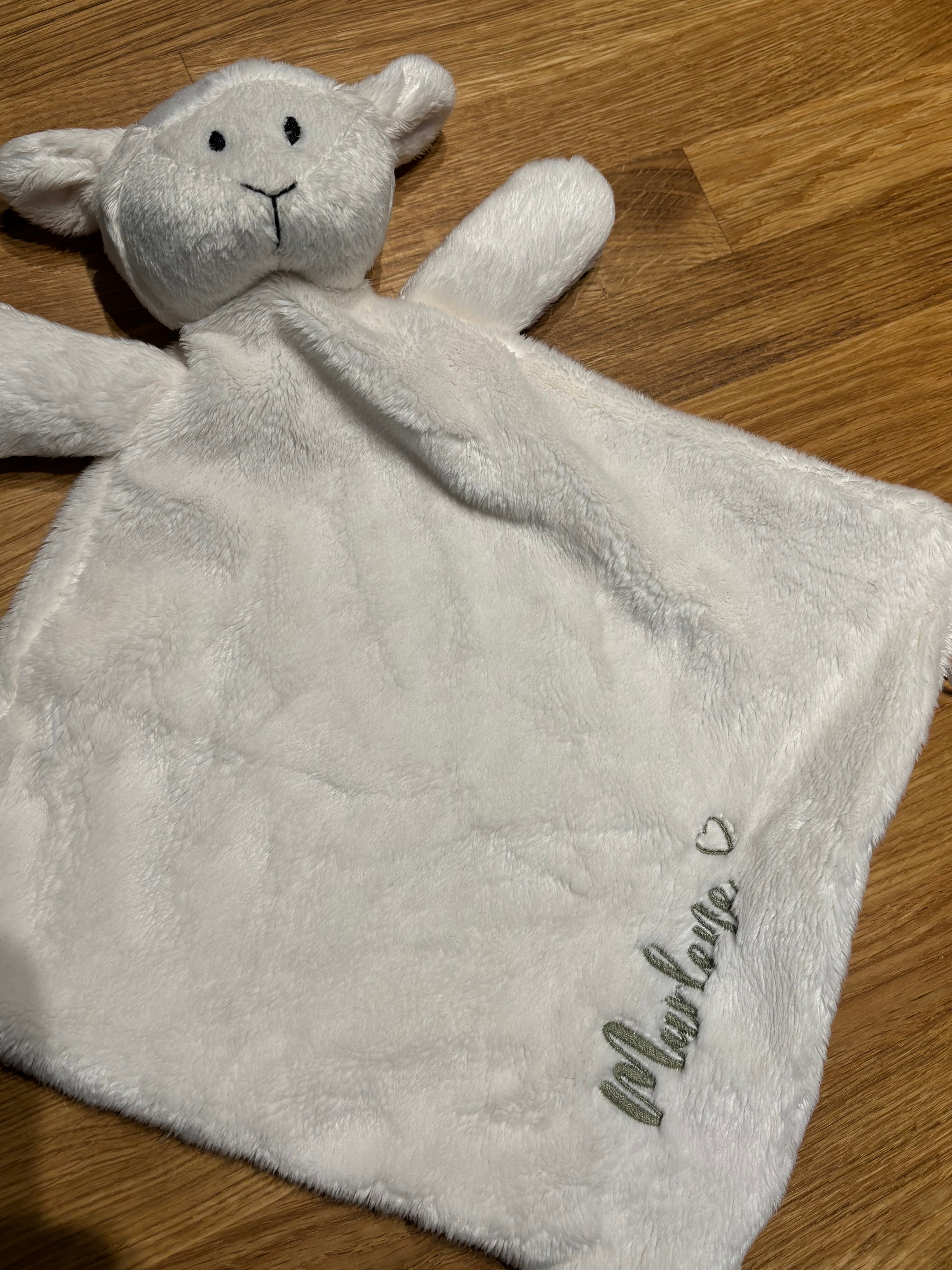 Ein weißes Schmusetuch mit einem grünen Garn bestickt Marlene mit Herz. 