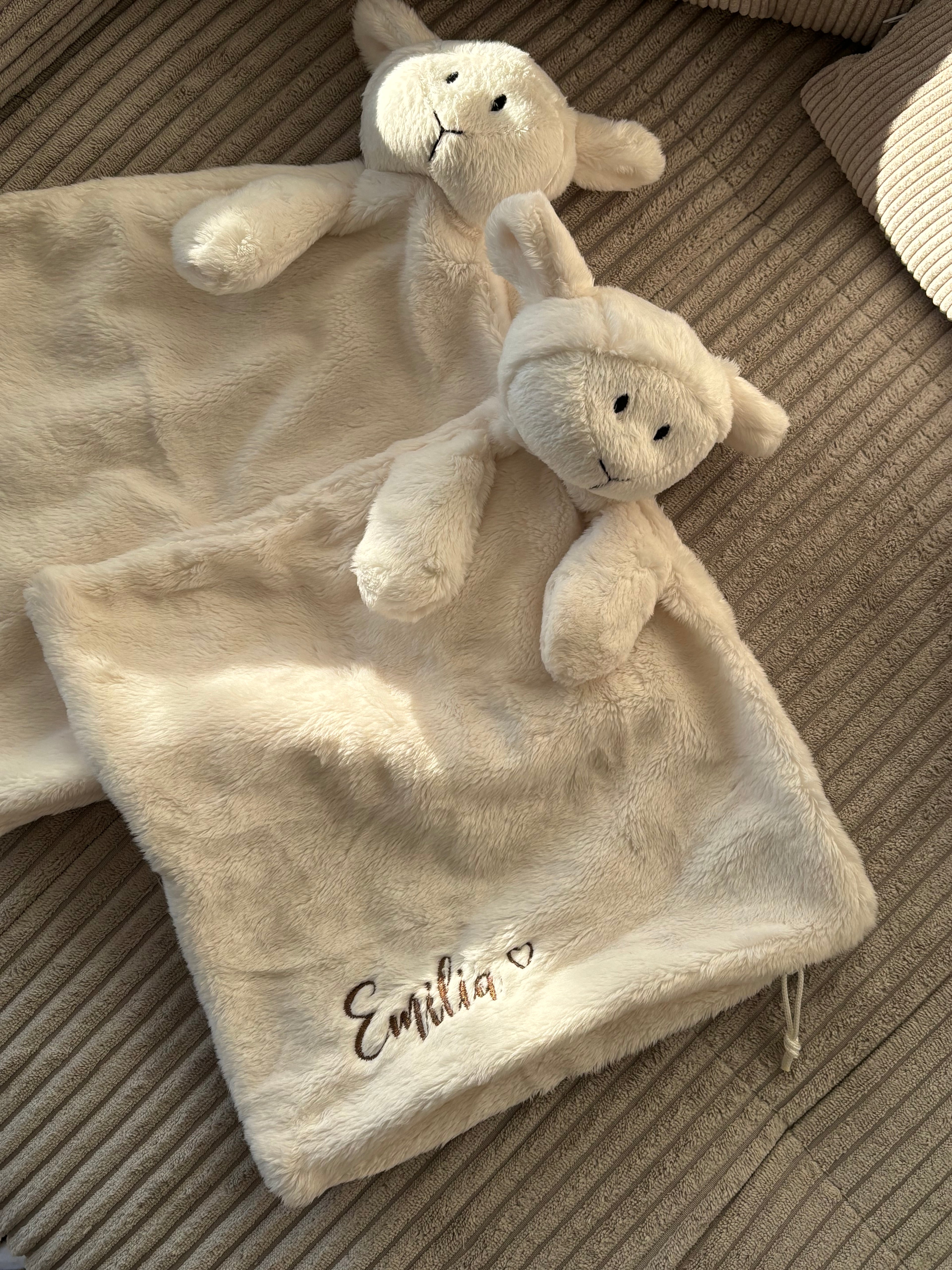 Zwei Lämmchen Schmusetücher. Am unteren Ende ist eine Schlaufe für den Schnuller. An der Seite ist der Name Emilia mit einem Herz in Braun gestickt.
