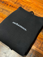 Ein schwarzer Hoodie mit einer Stickerei vorne auf der Brust: sarkasmus.