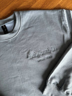 Ein Sweater in der Farbe Stone Blue mit einer Stickerei auf der linken Brustseite: Original D. since 1986.