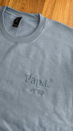 Ein Sweater in der Farbe Stone Blue mit einer Stickerei in der Farbe Stone Blue: Papa hoch 2 est. 2025.