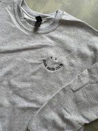 Ein Sweater in der Farbe Ash Heather mit einer dunkel grünen Stickerei Cool Dads Club.