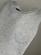 Ein Sweater in der Farbe Ash Heather mit einer hellblauen Stickerei Cool Dads Club.