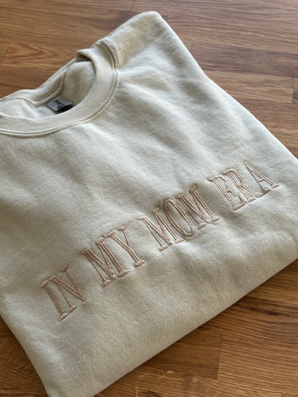 Ein Sweater in der Farbe Beige mit einem bestickten Wunschtext vorne auf der Brust mittig in beige "In my mom era".
