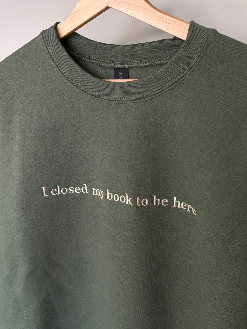 Ein grüner Sweater mit einem beigen Stick I closed my book to be here.