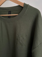 Ein Sweater in der Farbe Military Green mit einem Koordinaten Kreuz auf der linken Brust gestickt. Im Kreuz steht Dad est. 2025. Auf dem Ärmel ist der Kindername gestickt.