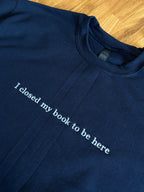 Ein Sweater in der Farbe navy blue mit einem weißen Stick auf der Brust "I closed my book to be here".