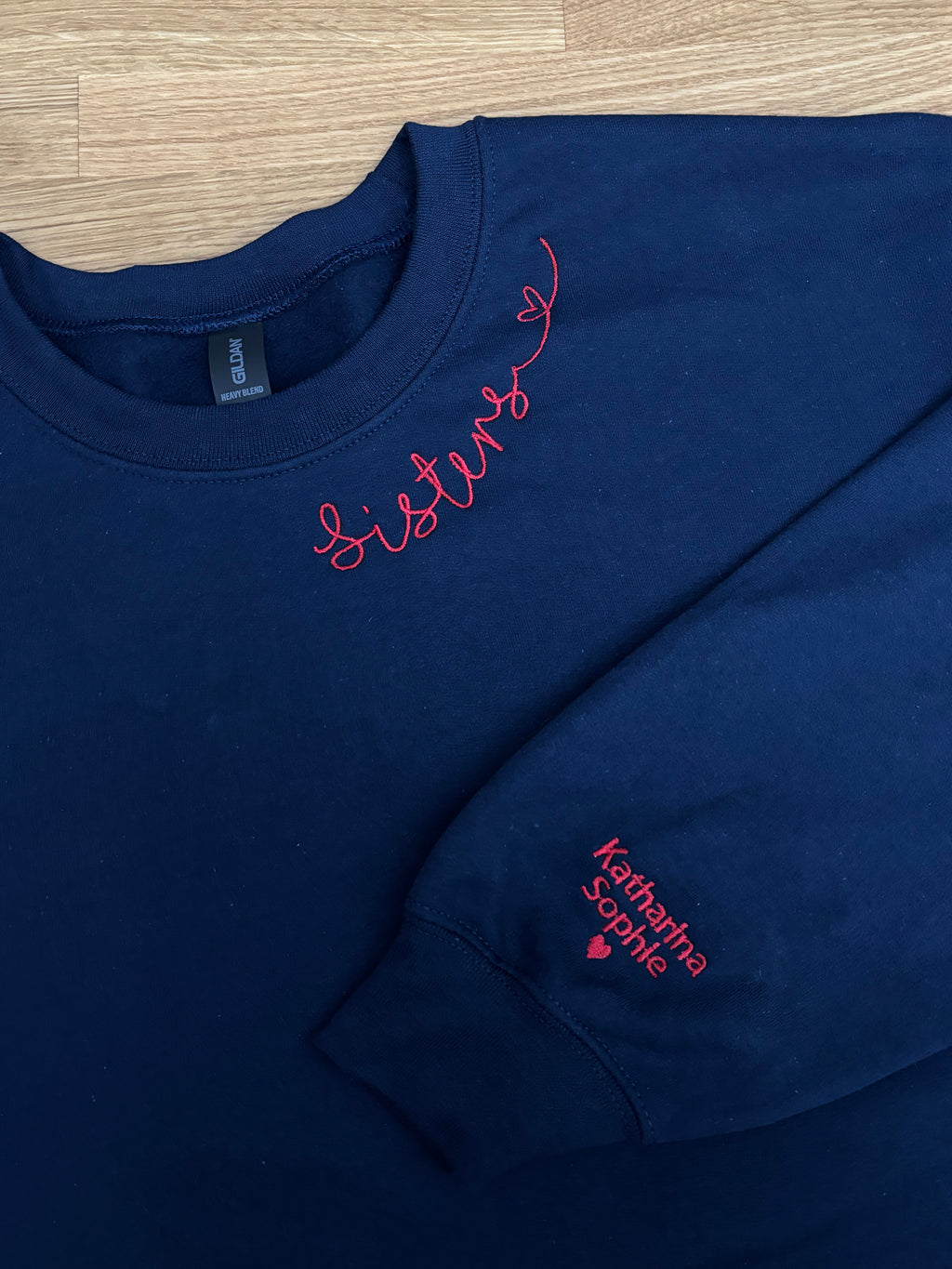 Ein Sweater in der Farbe Navy Blue mit einer roten Stickerei am Kragen und am Ärmel.