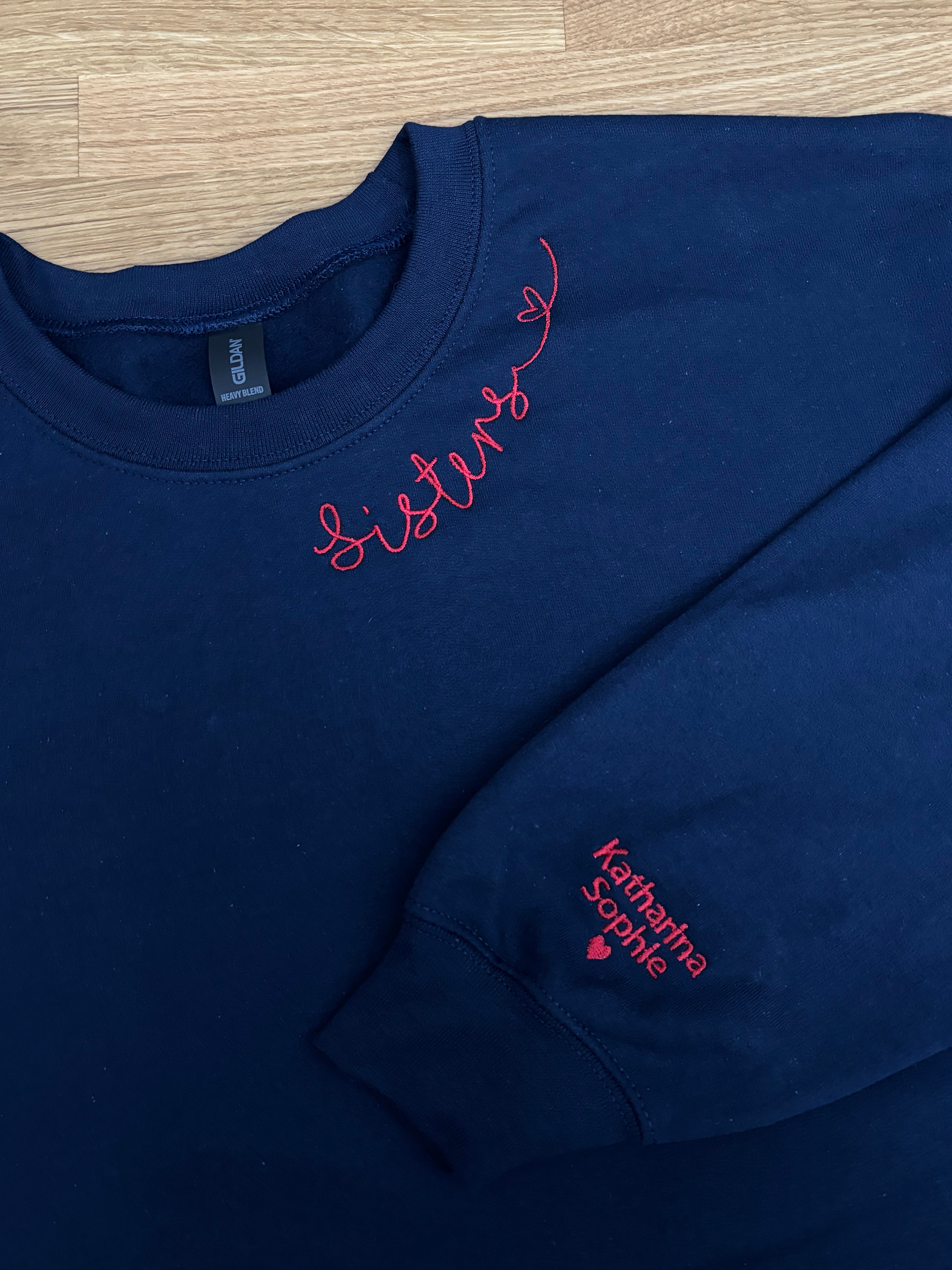 Ein Sweater in der Farbe Navy Blue mit einer roten Stickerei am Kragen und am Ärmel.