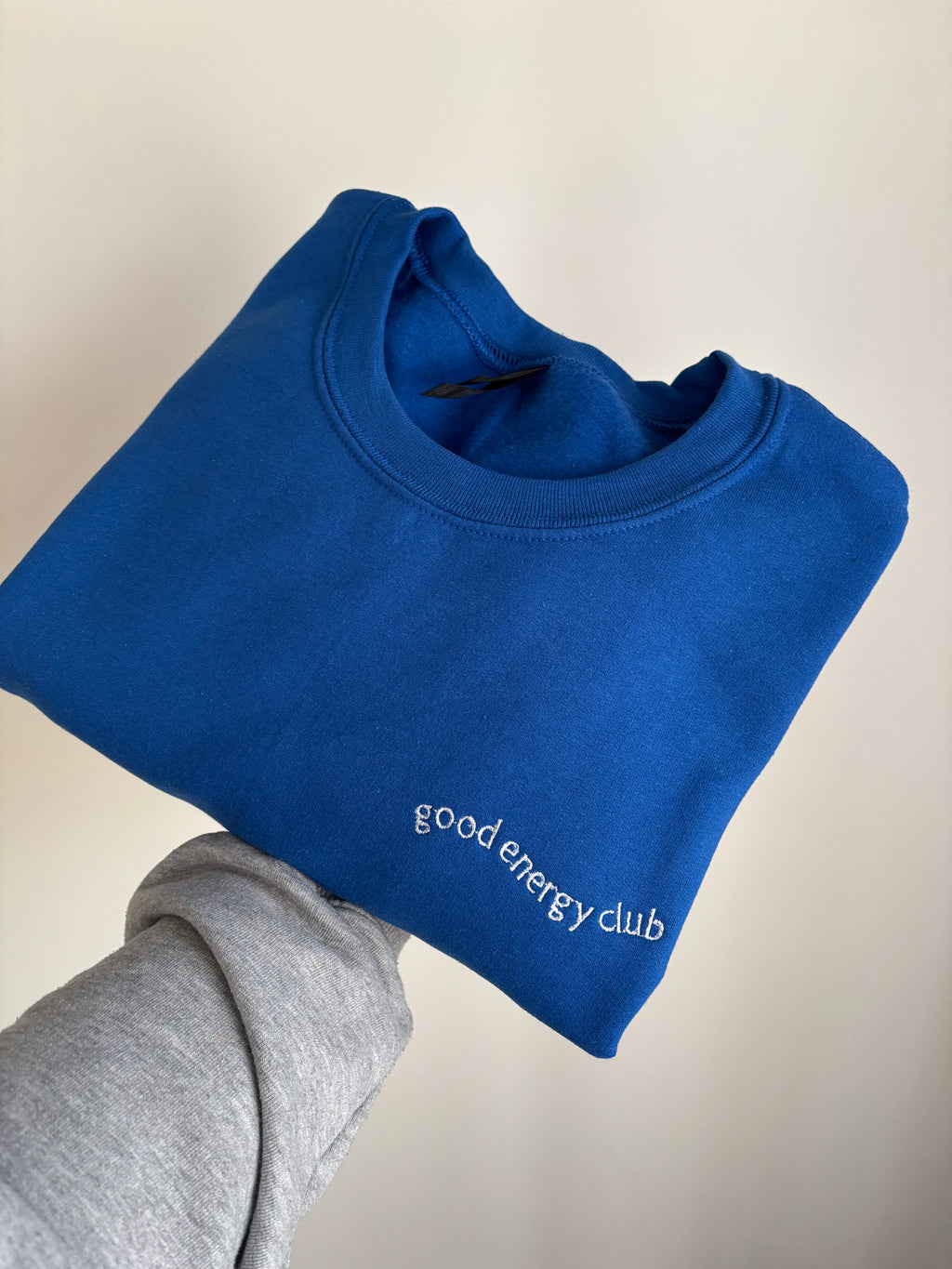 Ein Sweater in der Farbe Royal Blue mit einer Stickerek in weiß links: good Energy Club.