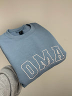 Ein bestickter Sweater in der Farbe Stone Blue OMA in der Garnfarbe poudre.