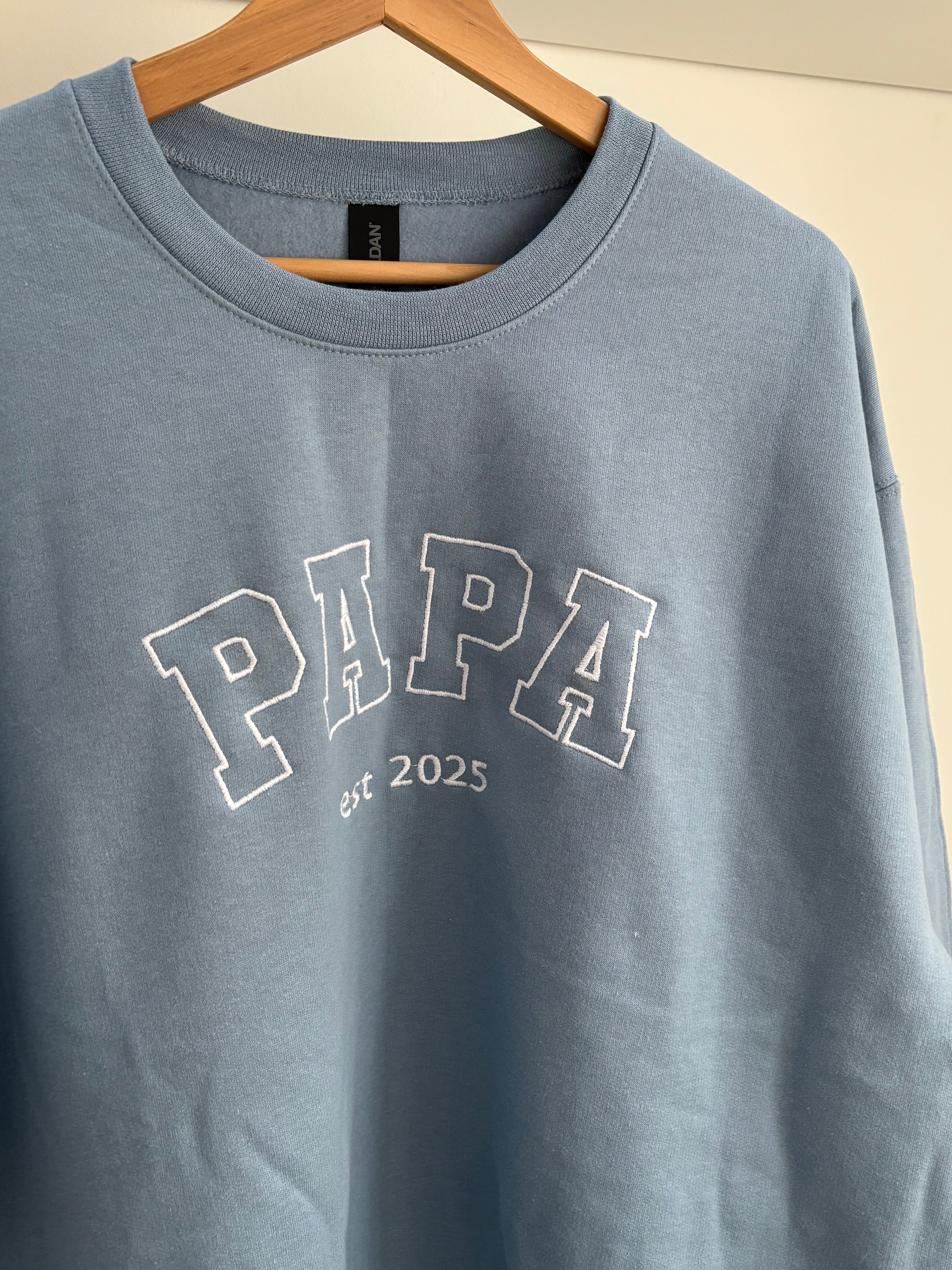 Ein bestickter Sweater in der Farbe Stone Blue PAPA est 2025 in der Garnfarbe weiß.