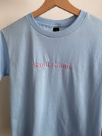 Ein Kinder T-Shirt in light blue mit einem rosa Stick "Smilla Junis".