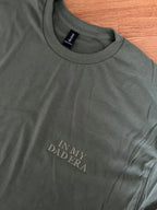 Ein T-Shirt in der Farbe Military Green mit einer Stickerei vorne links auf der Brust "In My Dad Era" in Großbuchstaben.
