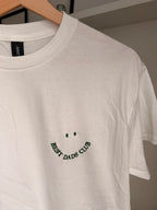 Ein T-Shirt in der Farbe Weiß mit einem Smiley bestickt "BEST DADS CLUB".