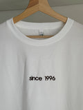 Ein T-Shirt in der Farbe weiß mit einer Stickerei vorne mittig in der Farbe Coffe Brown: since 1996.