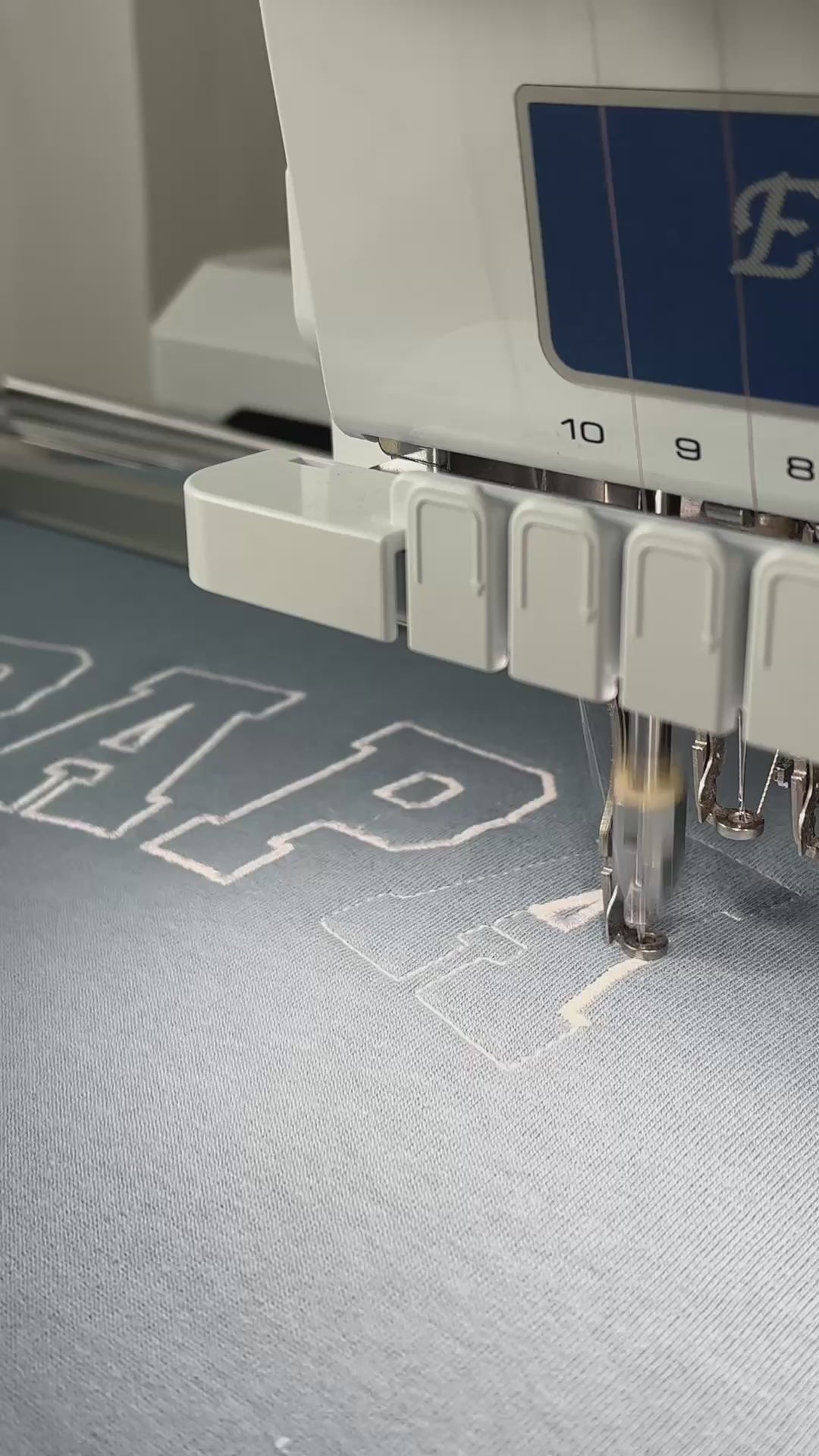 Ein Sweater wird mit bestickt mit dem Wunschtext Papa est. 2025 in der Garnfarbe Weiß.