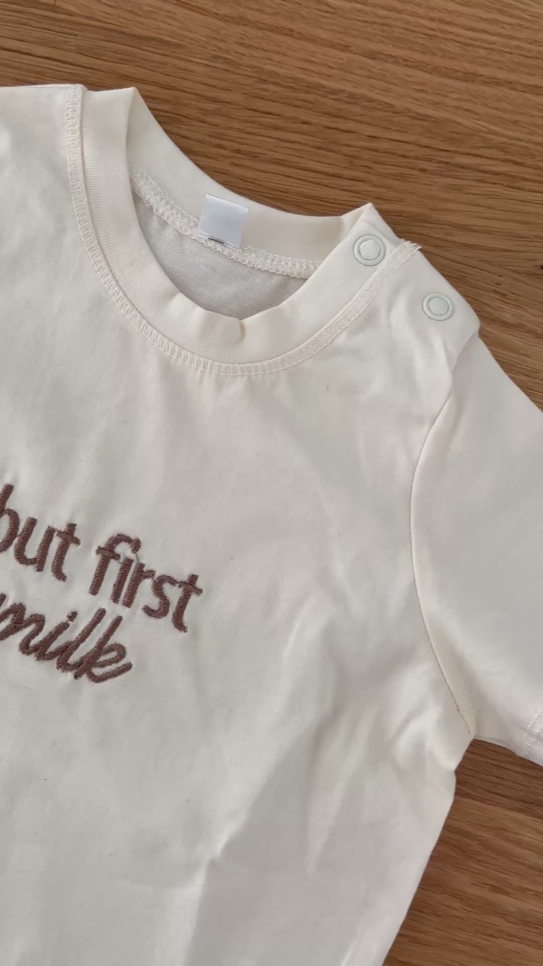 Beiges T.Shirt für Babys mit dem Stick in braun "but first milk".
